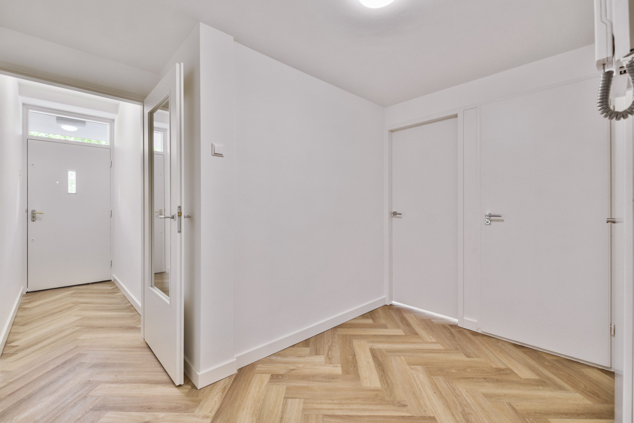 an empty interior area with white walls and laminate flooring
